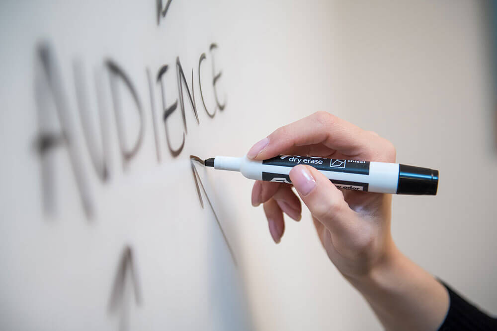 digital marketer writing "audience" on a dry erase board