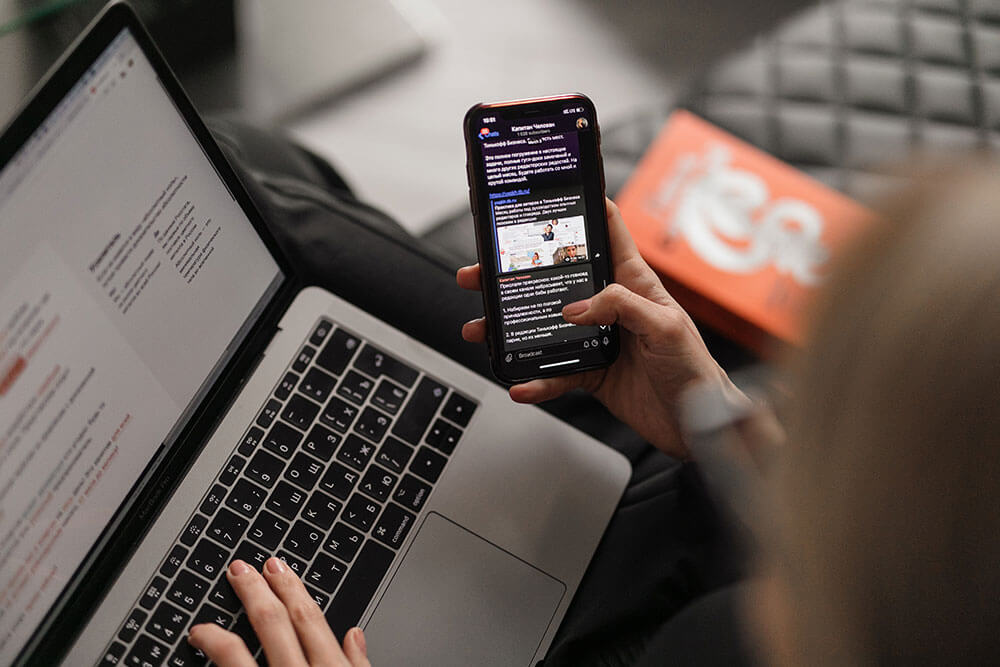 person using a phone and a laptop browsing the internet